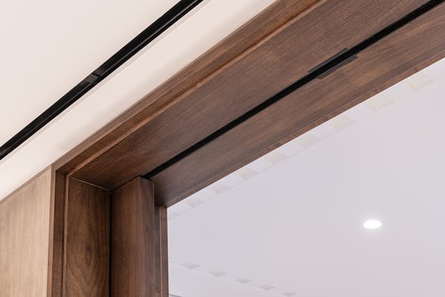 The track detail of a double pocket sliding door system set into a dark wood frame.