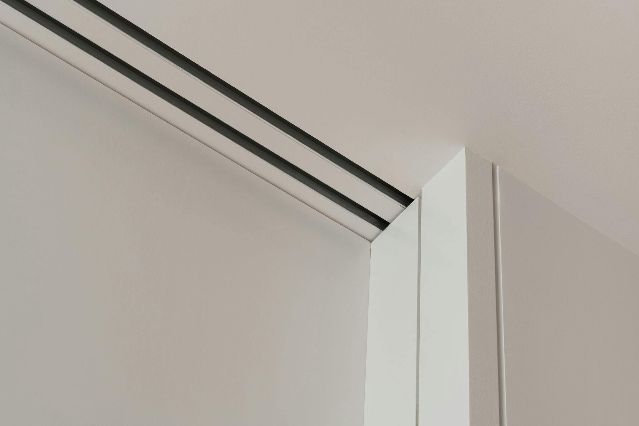 Two tracks of a double telescopic sliding door set in a white interior.