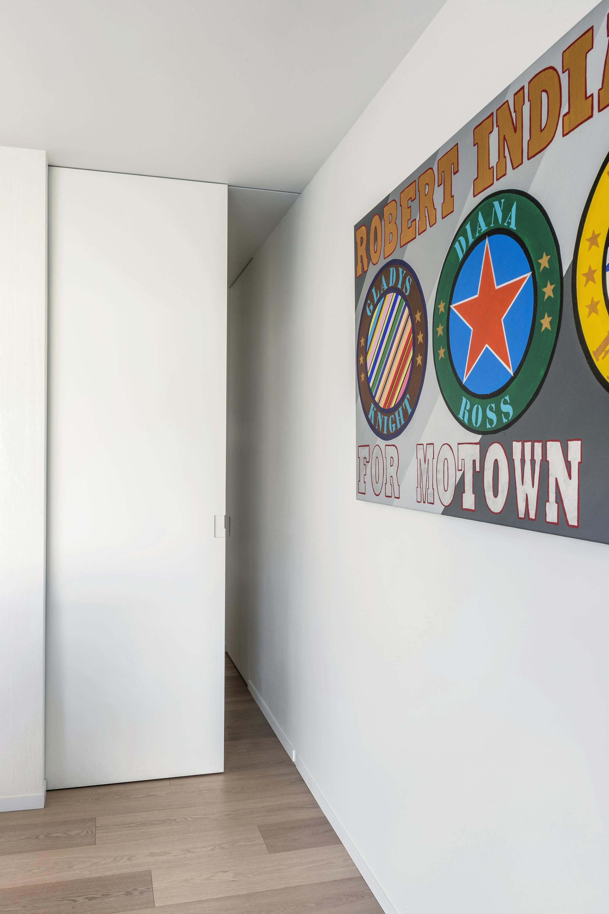 A white interior with a large motown poster and a white single sliding pocket door that is partially open.