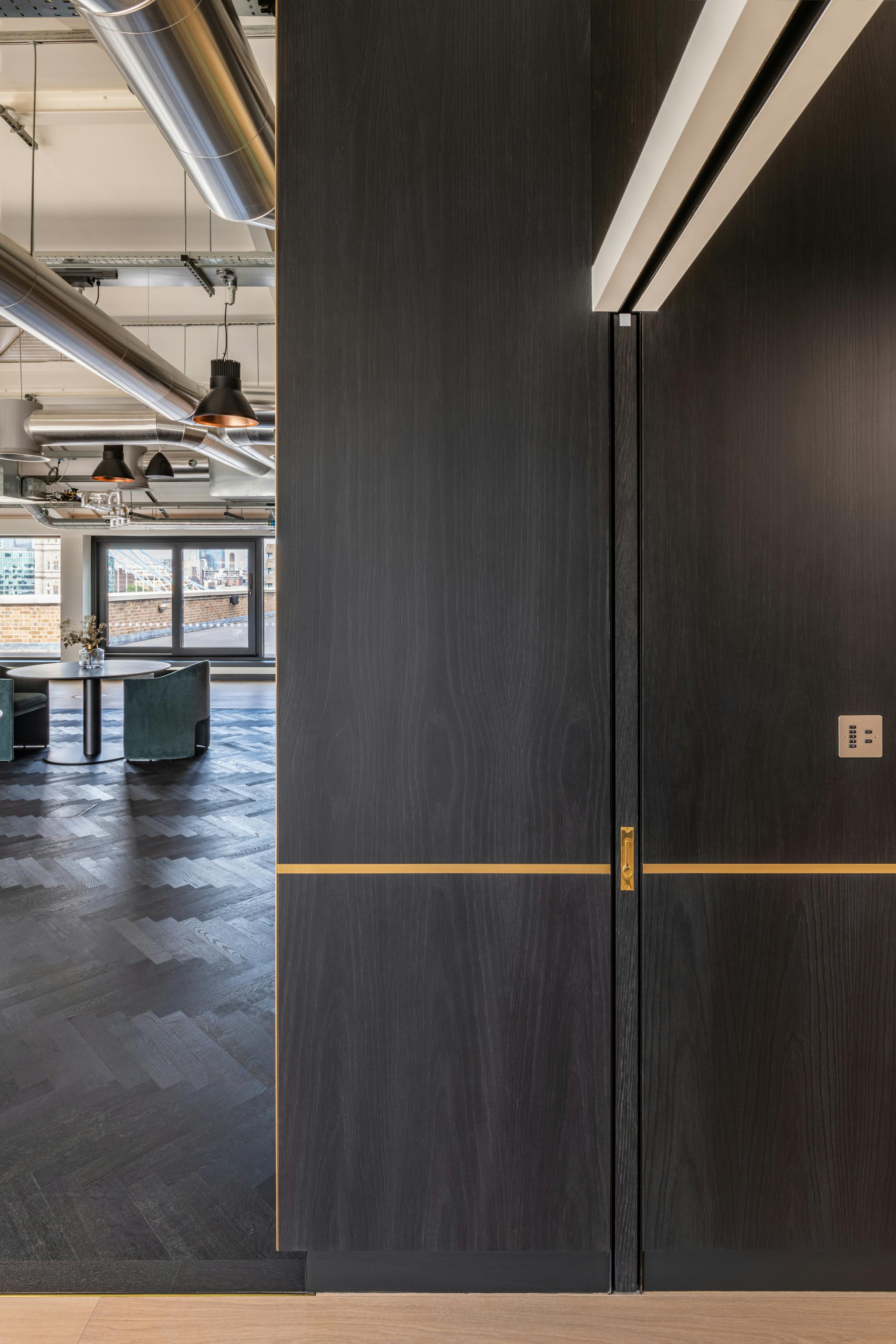 Side profile of a fully closed dark wood pocket sliding door in an office environment set into a dark wood wall.
