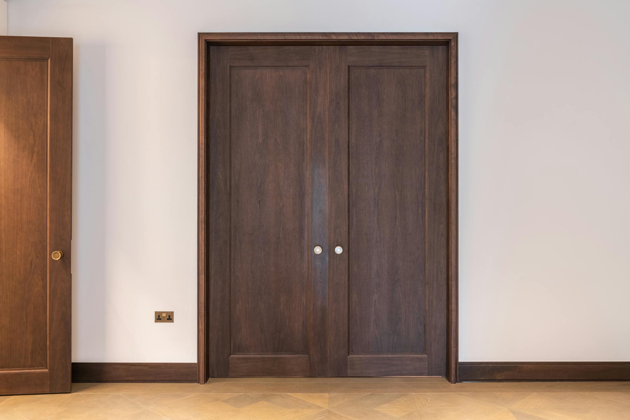 A luxury interior with fully closed set of heavy wooden pocket doors with solid brass ironmongery.